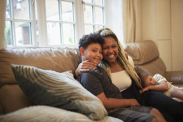 Portrait happy mother and son hugging on living room sofa - CAIF32720