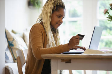 Frau mit Kreditkarte beim Online-Shopping am Laptop - CAIF32737