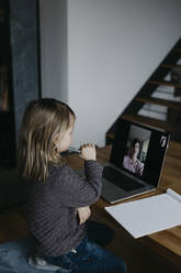 Mädchen besucht den Unterricht per Videoanruf auf dem Laptop zu Hause - LHPF01455