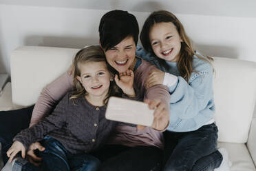 Happy family taking selfie through smart phone at home - LHPF01459