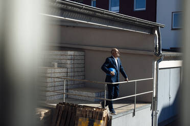 Geschäftsmann mit Schutzhelm auf einer Baustelle - JOSEF09705