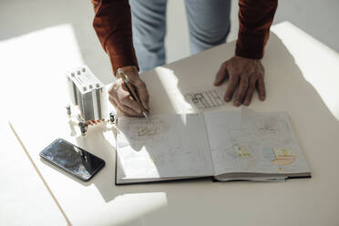 Hand of businessman writing in diary at desk - JOSEF09710