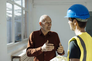 Architect discussing with construction worker at office - JOSEF09738