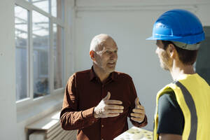 Architekt bespricht sich mit Bauarbeiter im Büro - JOSEF09738