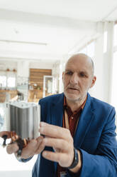 Senior engineer examining heating module in office - JOSEF09813