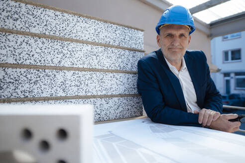 Geschäftsmann mit Schutzhelm an einem Bauplan auf einer Baustelle - JOSEF09840