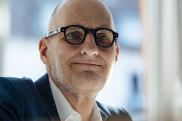 Smiling senior businessman wearing eyeglasses in office - JOSEF09856