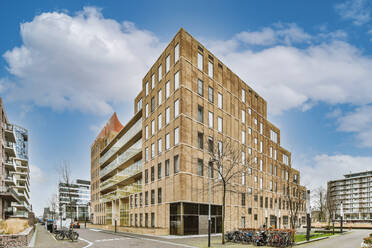 Creative design of modern multistory house exteriors against walkways under cloudy blue sky - ADSF34797