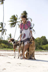 Frau streichelt Hunde am Strand - NDF01446