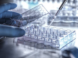 Scientist filling microplate with pipette in laboratory - ABRF00966