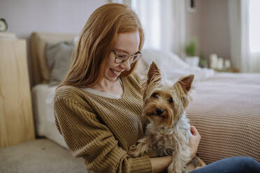 Glückliche Frau mit Hund, der zu Hause im Bett sitzt - HAPF03103