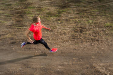 Young woman running on dirt road - STSF03230