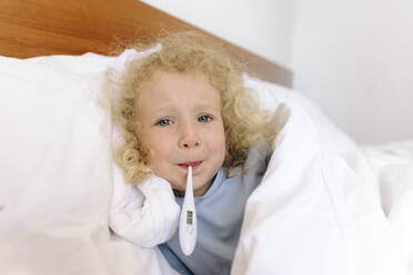 Girl with thermometer in mouth lying on bed at home - SIF00142