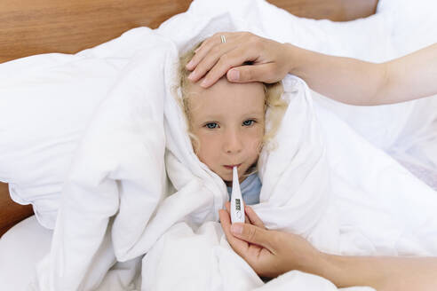 Krankes Mädchen, eingewickelt in eine Decke, liegt zu Hause auf dem Bett - SIF00145