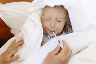 Sick daughter avoiding to use thermometer by mother in bedroom - SIF00150