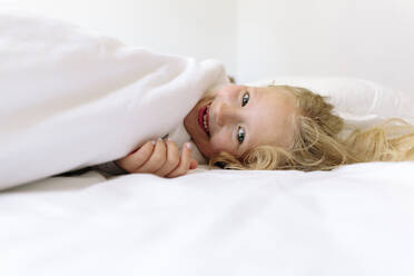 Glückliches Mädchen auf dem Bett liegend im Schlafzimmer - SIF00158