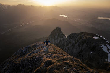 Wanderer, der bei Sonnenuntergang auf einen Berggipfel steigt - MALF00404