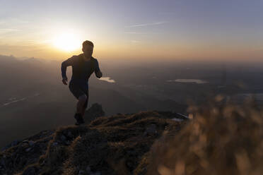 Silhouette hiker running on mountain at sunset - MALF00409