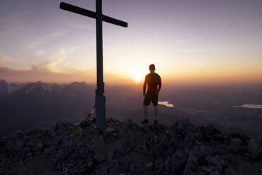 Silhouette Mann vor Gipfelkreuz auf Berg stehend - MALF00418