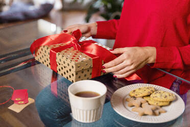 Frau sitzt mit Weihnachtsgeschenk am Tisch - EIF04108