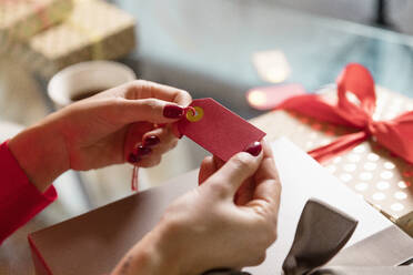 Hands of woman holding gift tag at home - EIF04113