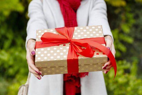 Junge Frau gibt Weihnachtsgeschenk mit roter Schleife - EIF04148