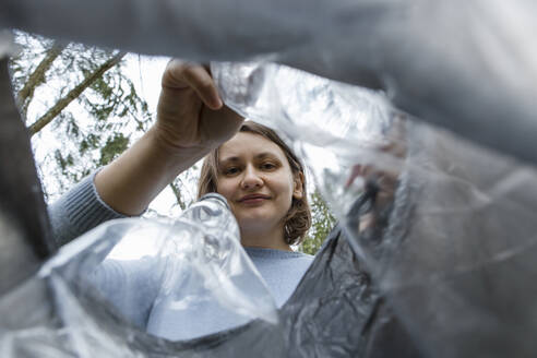 Frau packt Plastikflaschen in Müllsack - LLUF00545