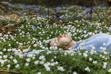 Frau inmitten von Wildblumen auf einer Wiese liegend - LLUF00546