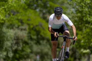 Engagierter reifer Sportler auf dem Fahrrad an einem sonnigen Tag - OCMF02397