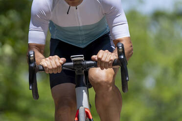 Athlete in sports clothing riding bicycle on sunny day - OCMF02400