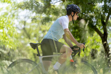 Älterer Sportler mit Helm auf dem Fahrrad - OCMF02403