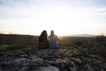 Junges Paar sitzt auf Felsen und bewundert den Sonnenuntergang - DAMF00938