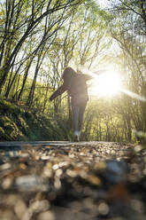 Woman walking on road in forest - DAMF00940