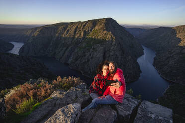 Glückliches Paar, das auf dem Gipfel eines Berges ein Selfie mit seinem Smartphone macht - DAMF00946