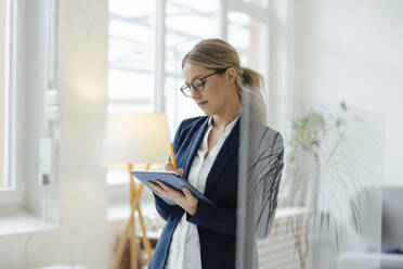 Blond businesswoman using tablet PC in office - JOSEF09963