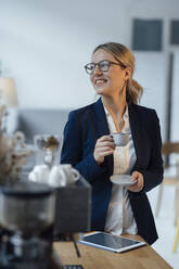 Lächelnde Geschäftsfrau mit Kaffeetasse im Büro - JOSEF09969