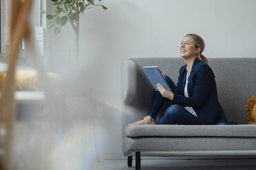 Lächelnde Geschäftsfrau mit Tablet-PC auf dem Sofa im Büro - JOSEF09983