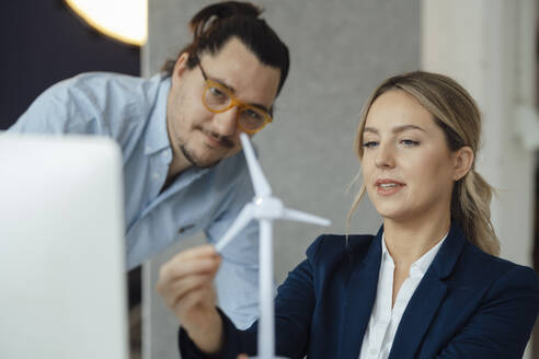 Ingenieur diskutiert mit einem Kollegen über ein Windradmodell im Büro - JOSEF09984