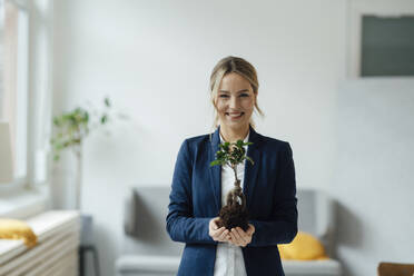 Lächelnde Geschäftsfrau mit Pflanze im Büro - JOSEF09987