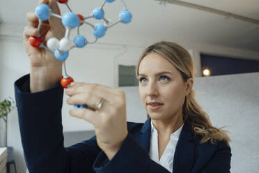 Businesswoman analyzing molecular structure model in office - JOSEF09994