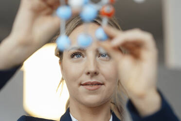 Businesswoman examining molecular model in office - JOSEF09997