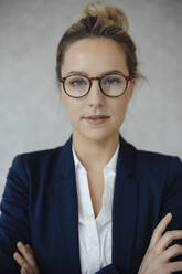 Businesswoman with arms crossed against gray background - JOSEF09998