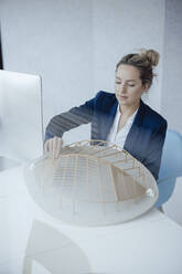 Businesswoman analyzing leaf shape model at desk - JOSEF10008