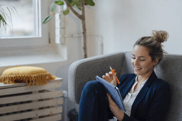Glückliche Geschäftsfrau mit Tablet-PC auf dem Sofa im Büro - JOSEF10026