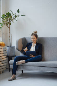 Geschäftsfrau mit Tablet-PC auf dem Sofa im Büro sitzend - JOSEF10029
