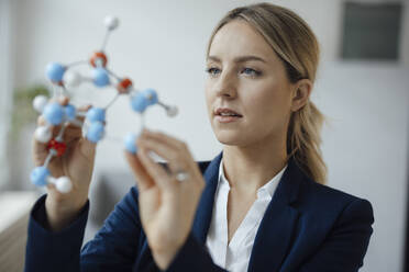 Businesswoman examining molecular model in office - JOSEF10051