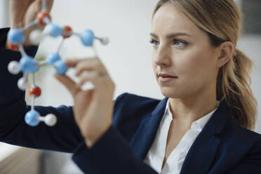 Geschäftsfrau, die ein molekulares Modell im Büro analysiert - JOSEF10052