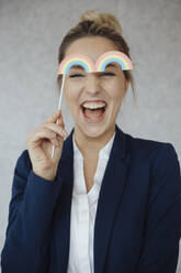 Glückliche Geschäftsfrau mit Regenbogenrequisite im Büro - JOSEF10065