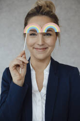 Lächelnde Geschäftsfrau mit Regenbogenrequisite im Büro - JOSEF10066