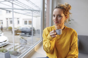 Frau mit Kaffeetasse auf der Fensterbank zu Hause - JOSEF10084